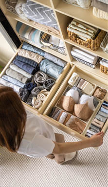 A young woman chooses which bra to wear while standing in front of a neatly arranged wardrobe. The concept of underwear storage and space organization. Top view.